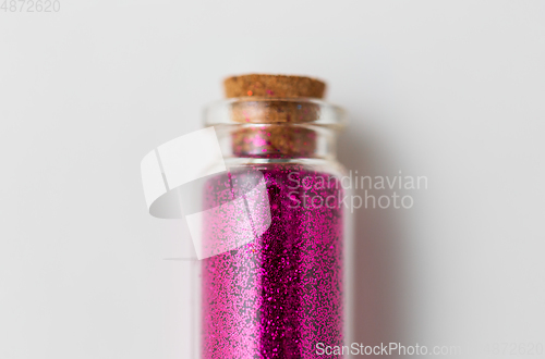 Image of pink glitters in bottle over white background