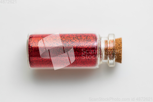 Image of red glitters in bottle over white background