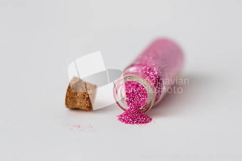 Image of pink glitters poured from small glass bottle