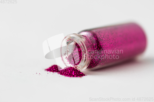 Image of pink glitters poured from small glass bottle