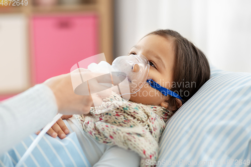 Image of mother and sick daughter with oxygen mask in bed