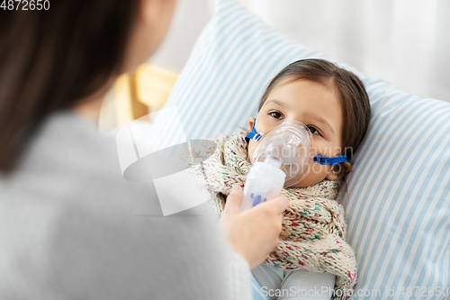 Image of mother and sick daughter with oxygen mask in bed