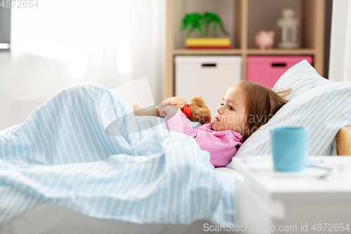 Image of sick little girl lying in bed at home