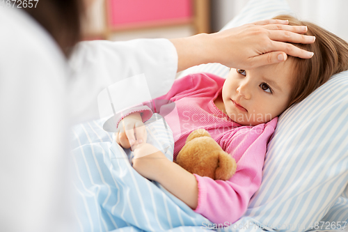 Image of doctor measuring sick girl's temperature at home