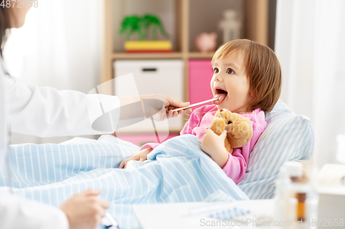 Image of doctor checking sick girl's throat at home