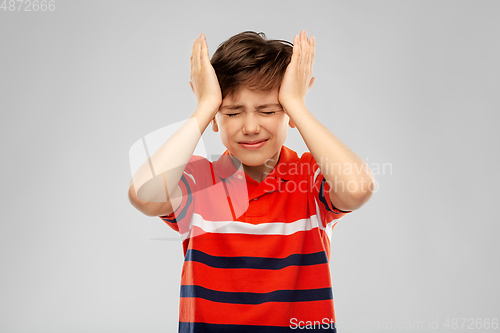 Image of stressed boy in red polo t-shirt having headache