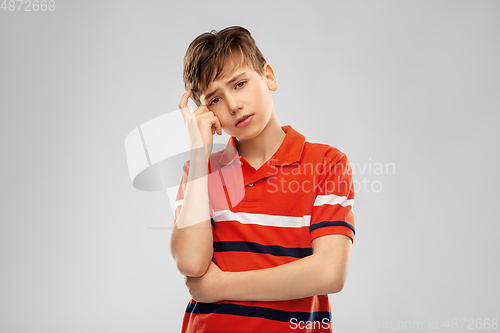 Image of portrait of sad thinking boy in red polo t-shirt