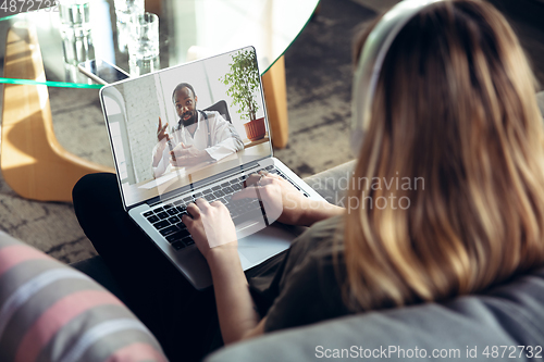 Image of Young woman getting online medical help and advice during videocall with doctor checking symtoms aand explaining the drug\'s reciepes