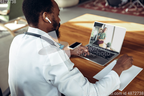 Image of Doctor advising the patient online with laptop. African-american doctor during his videocall, work with patients, explaining recipes for drug.