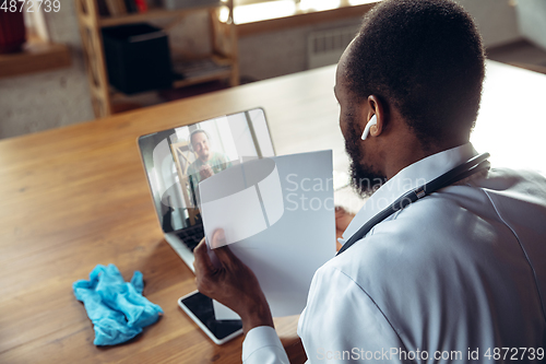Image of Doctor advising the patient online with laptop. African-american doctor during his videocall, work with patients, explaining recipes for drug.