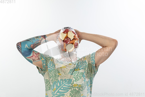 Image of Male face covered with oilcloth, cellophane and unhealthy food, hard to breathe. People lost their faces, can\'t notice the environmental pollution made by themself.