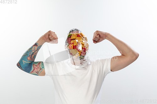 Image of Male face covered with oilcloth, cellophane and unhealthy food, hard to breathe. People lost their faces, can\'t notice the environmental pollution made by themself.