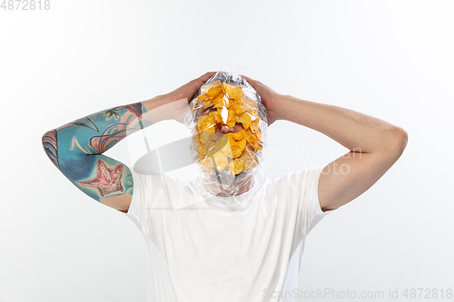 Image of Male face covered with oilcloth, cellophane and unhealthy food, hard to breathe. People lost their faces, can\'t notice the environmental pollution made by themself.