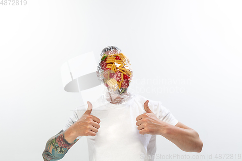 Image of Male face covered with oilcloth, cellophane and unhealthy food, hard to breathe. People lost their faces, can\'t notice the environmental pollution made by themself.