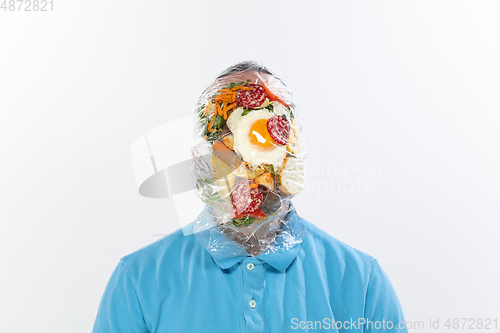 Image of Male face covered with oilcloth, cellophane and unhealthy food, hard to breathe. People lost their faces, can\'t notice the environmental pollution made by themself.