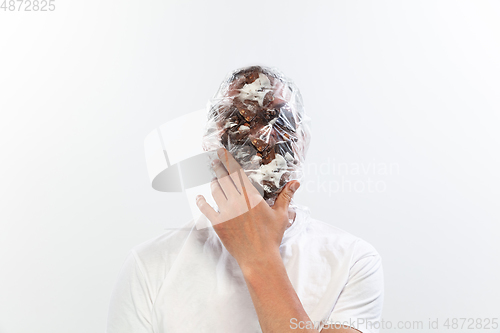 Image of Male face covered with oilcloth, cellophane and unhealthy food, hard to breathe. People lost their faces, can\'t notice the environmental pollution made by themself.