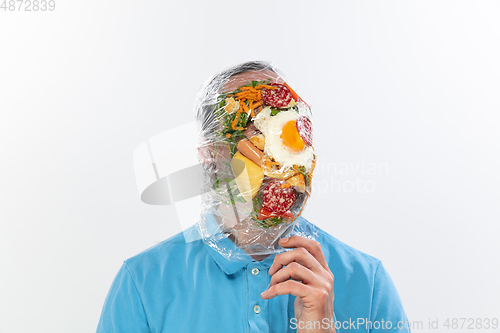 Image of Male face covered with oilcloth, cellophane and unhealthy food, hard to breathe. People lost their faces, can\'t notice the environmental pollution made by themself.