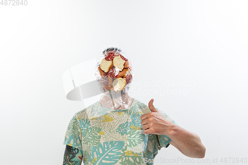 Image of Male face covered with oilcloth, cellophane and unhealthy food, hard to breathe. People lost their faces, can\'t notice the environmental pollution made by themself.