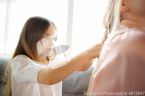 Image of Mother and daughter, sisters have quite, beauty and fun day together at home. Comfort and togetherness. Making a hairstyle.