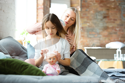 Image of Mother and daughter, sisters have quite, beauty and fun day together at home. Comfort and togetherness. Making a hairstyle.