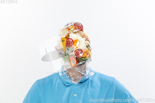 Image of Male face covered with oilcloth, cellophane and unhealthy food, hard to breathe. People lost their faces, can\'t notice the environmental pollution made by themself.