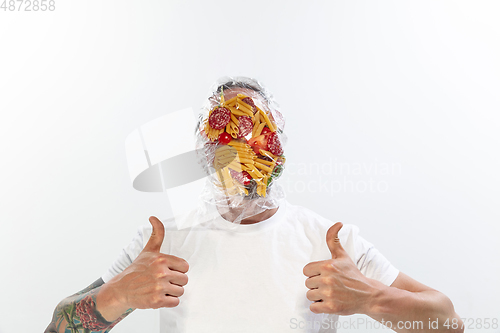 Image of Male face covered with oilcloth, cellophane and unhealthy food, hard to breathe. People lost their faces, can\'t notice the environmental pollution made by themself.