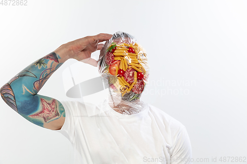 Image of Male face covered with oilcloth, cellophane and unhealthy food, hard to breathe. People lost their faces, can\'t notice the environmental pollution made by themself.