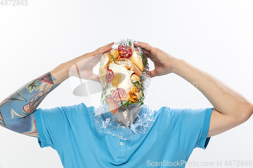 Image of Male face covered with oilcloth, cellophane and unhealthy food, hard to breathe. People lost their faces, can\'t notice the environmental pollution made by themself.