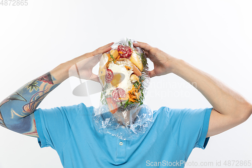 Image of Male face covered with oilcloth, cellophane and unhealthy food, hard to breathe. People lost their faces, can\'t notice the environmental pollution made by themself.