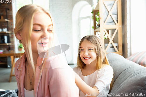 Image of Mother and daughter, sisters have quite, beauty and fun day together at home. Comfort and togetherness. Making a hairstyle.