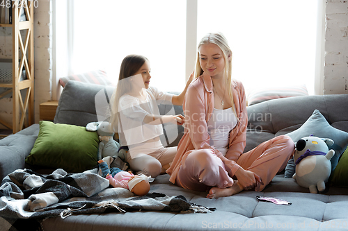 Image of Mother and daughter, sisters have quite, beauty and fun day together at home. Comfort and togetherness. Making a hairstyle.