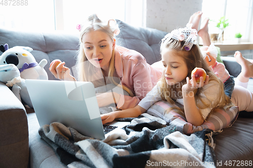 Image of Mother and daughter, sisters have quite, beauty and fun day together at home. Comfort and togetherness. Watching series, eating healthy food, do a hairstyle