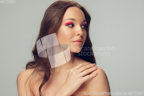Image of Close up of beautiful young woman with long healthy curly hair and bright make up isolated on grey studio backgroud, looking at side