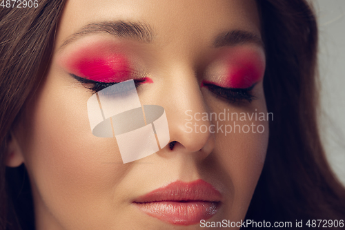 Image of Close up of beautiful young woman with long healthy curly hair and bright make up isolated on grey studio backgroud