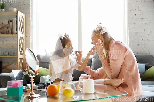 Image of Mother and daughter, sisters have quite, beauty and fun day together at home. Comfort and togetherness. Do a make up, using cosmetics, masks, moisturizers, brushes and lipsticks