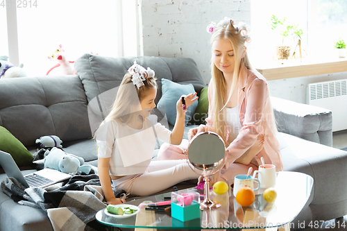 Image of Mother and daughter, sisters have quite, beauty and fun day together at home. Comfort and togetherness. Do a make up, using cosmetics, masks, moisturizers, brushes and lipsticks