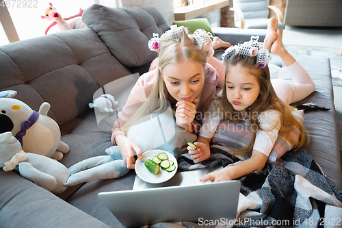 Image of Mother and daughter, sisters have quite, beauty and fun day together at home. Comfort and togetherness. Watching series, eating healthy food, do a hairstyle