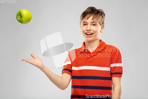 Image of portrait of happy smiling boy throwing green apple