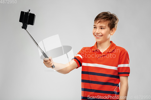 Image of boy taking picture with smartphone on selfie stick