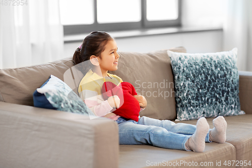 Image of happy little girl with heart shaped pillow at home