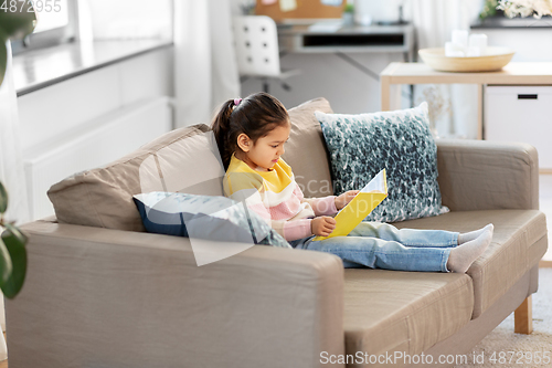 Image of little girl reading book at home