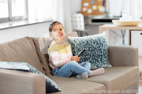 Image of happy smiling little girl with smartphone at home