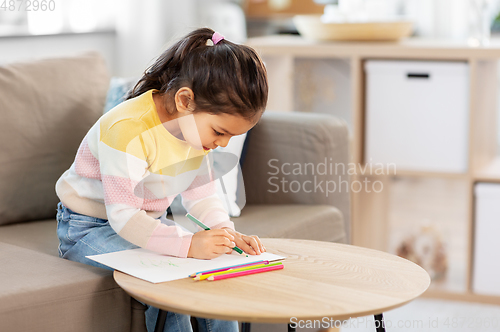Image of little girl drawing with coloring pencils at home