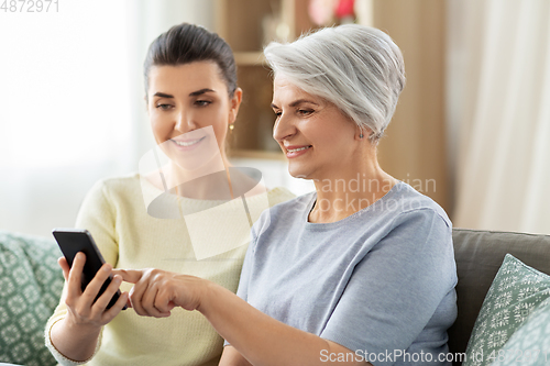 Image of daughter and senior mother with smartphone at home