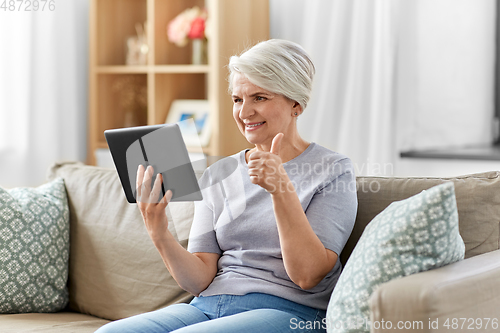 Image of senior woman having video chat on tablet pc