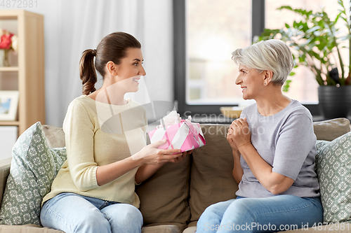 Image of adult daughter giving present to her senior mother