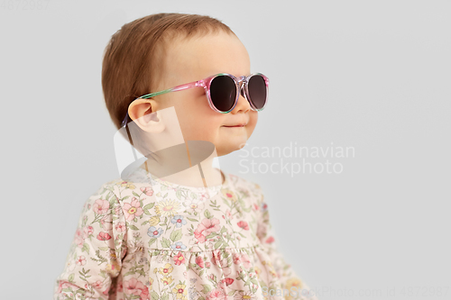 Image of happy little baby girl in sunglasses over grey