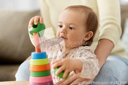 Image of lovely baby girl playing with toy pyramid at home