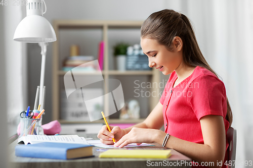 Image of student girl with ruler drawing line in notebook