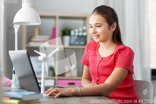 Image of girl with laptop and wind turbine toy at home